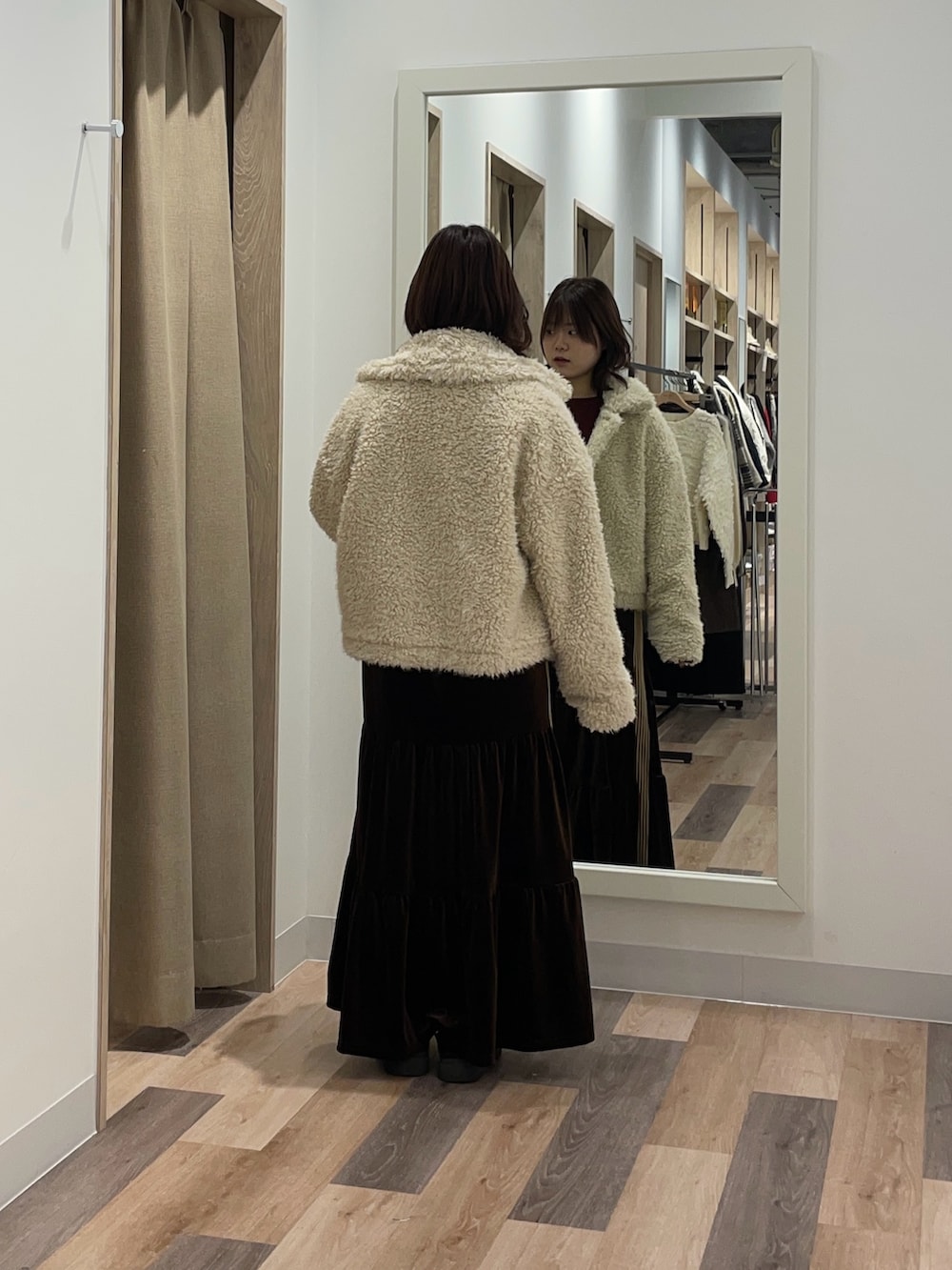 レッド系のニット/セーター、ホワイト系のブルゾン、ブラウン系のスカートを着用したレディースの冬コーディネートの3枚目の写真