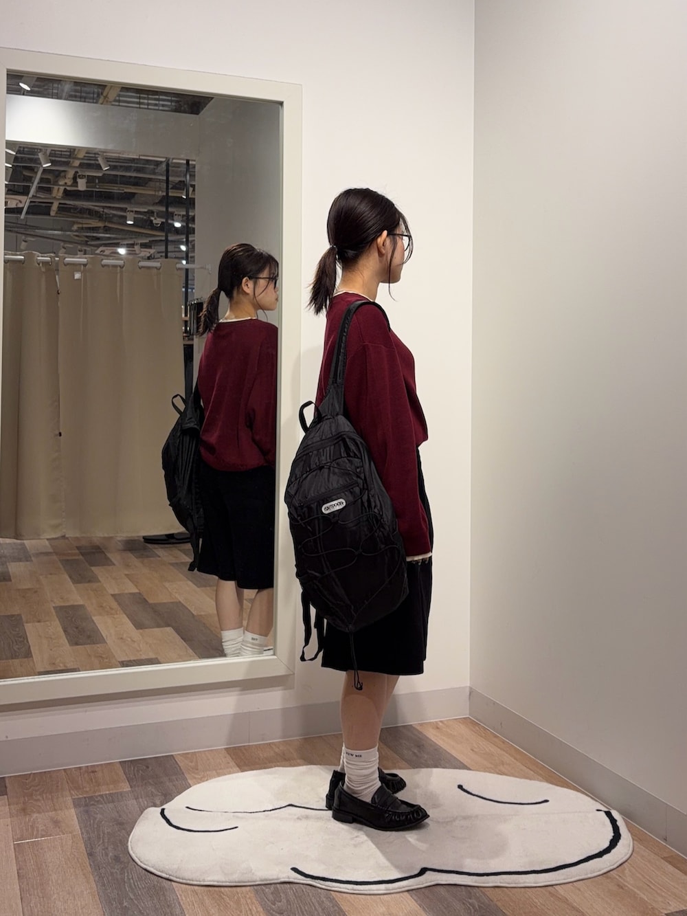 レッド系のニット/セーター、ブラック系のバックパック/リュック、ブラック系のその他シューズを着用したレディースの秋コーディネートの2枚目の写真