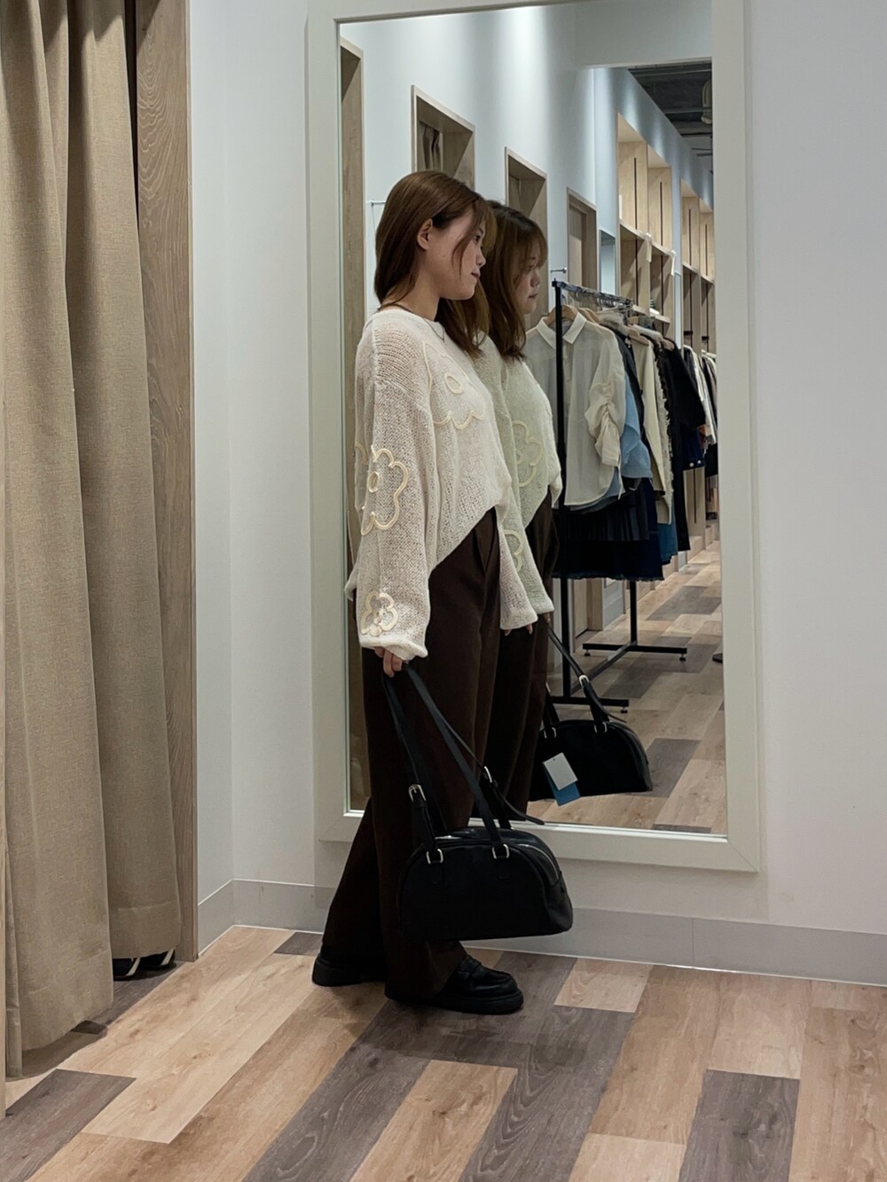 レッド系のニット/セーター、ブラック系のスラックス、ブラウン系のボストンバッグを着用したレディースの秋コーディネートの2枚目の写真