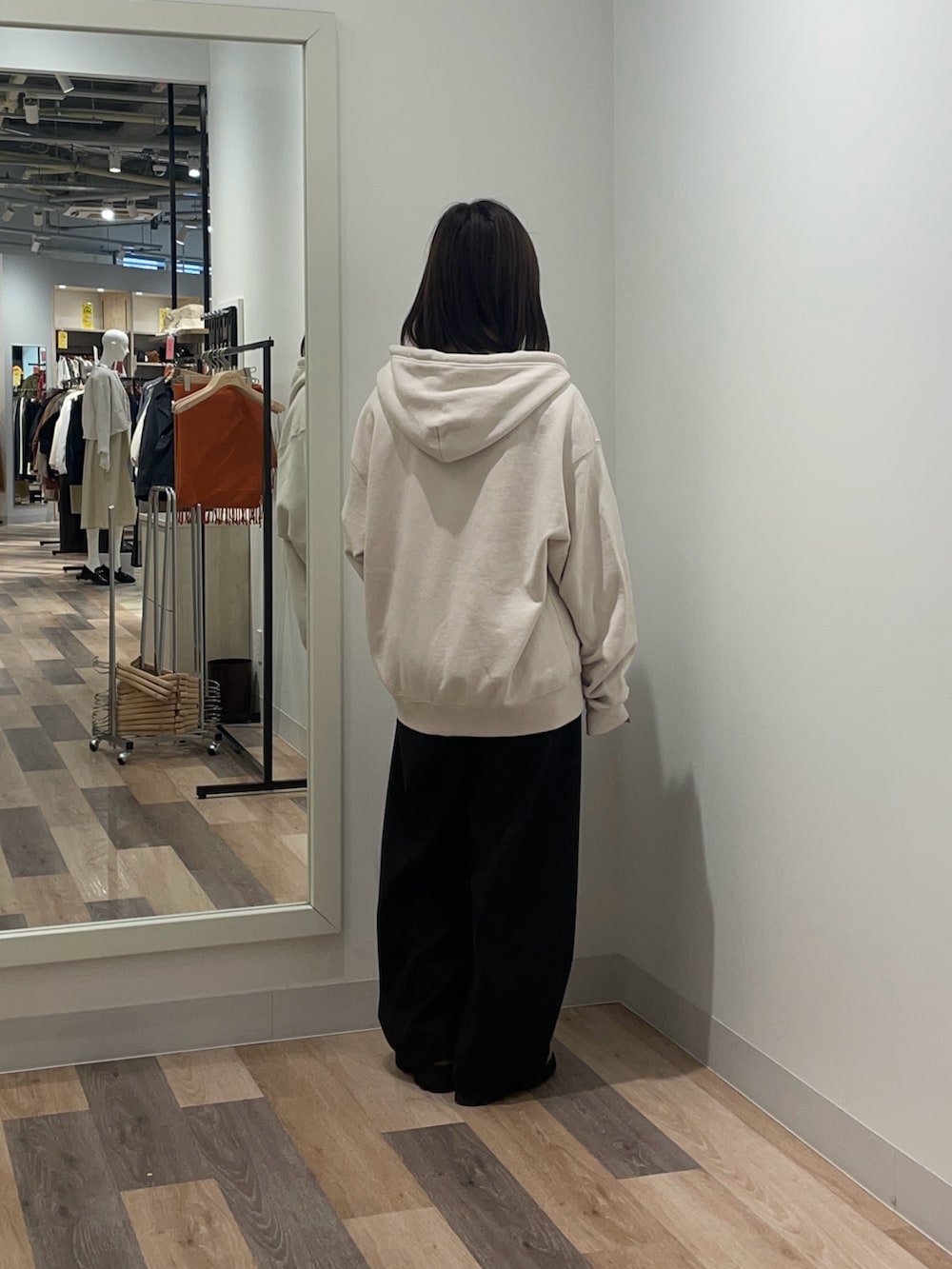 ホワイト系のパーカー、ブラック系のスラックスを着用したレディースの冬コーディネートの3枚目の写真