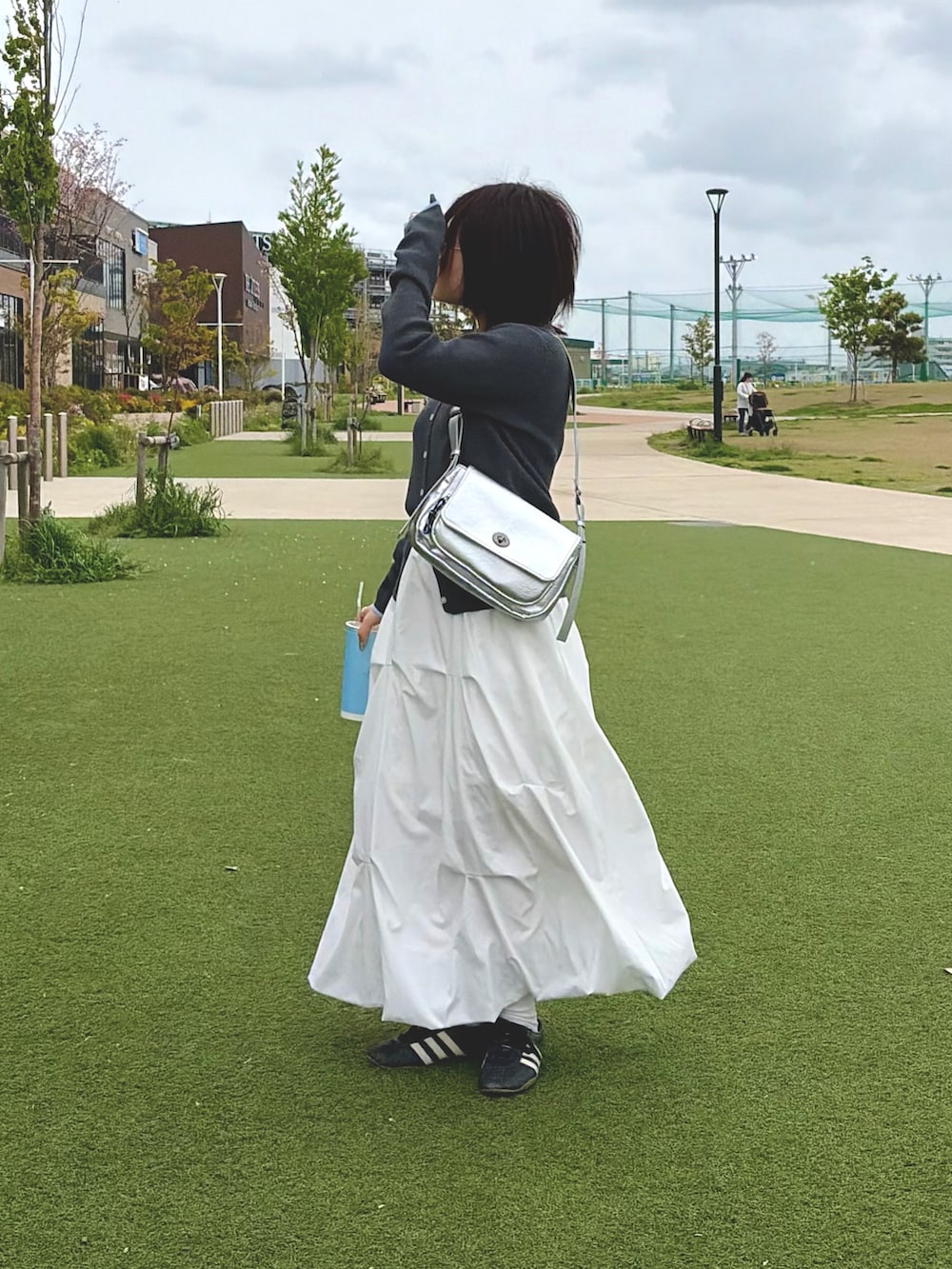 グレー系のカーディガン/ボレロ、ホワイト系のスカート、シルバー系のトートバッグを着用したレディースの春コーディネートの2枚目の写真