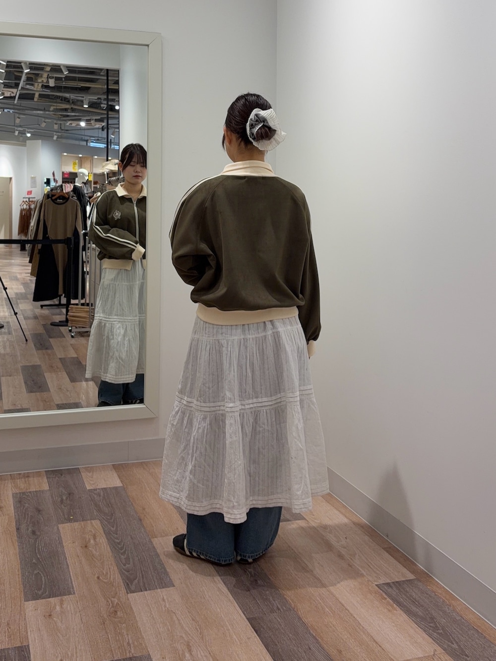 ホワイト系のスカート、ブルー系のデニムパンツ、グリーン系のブルゾンを着用したレディースの冬コーディネートの3枚目の写真