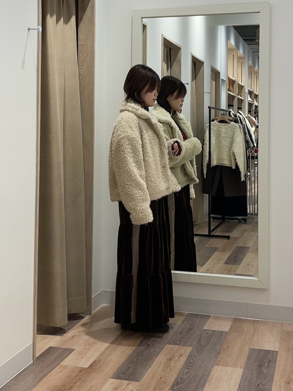 レッド系のニット/セーター、ホワイト系のブルゾン、ブラウン系のスカートを着用したレディースの冬コーディネートの2枚目の写真