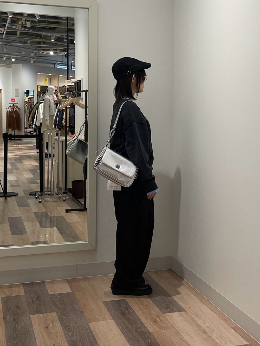 グレー系のニット/セーター、グレー系のスラックス、シルバー系のトートバッグを着用したレディースの冬コーディネートの2枚目の写真