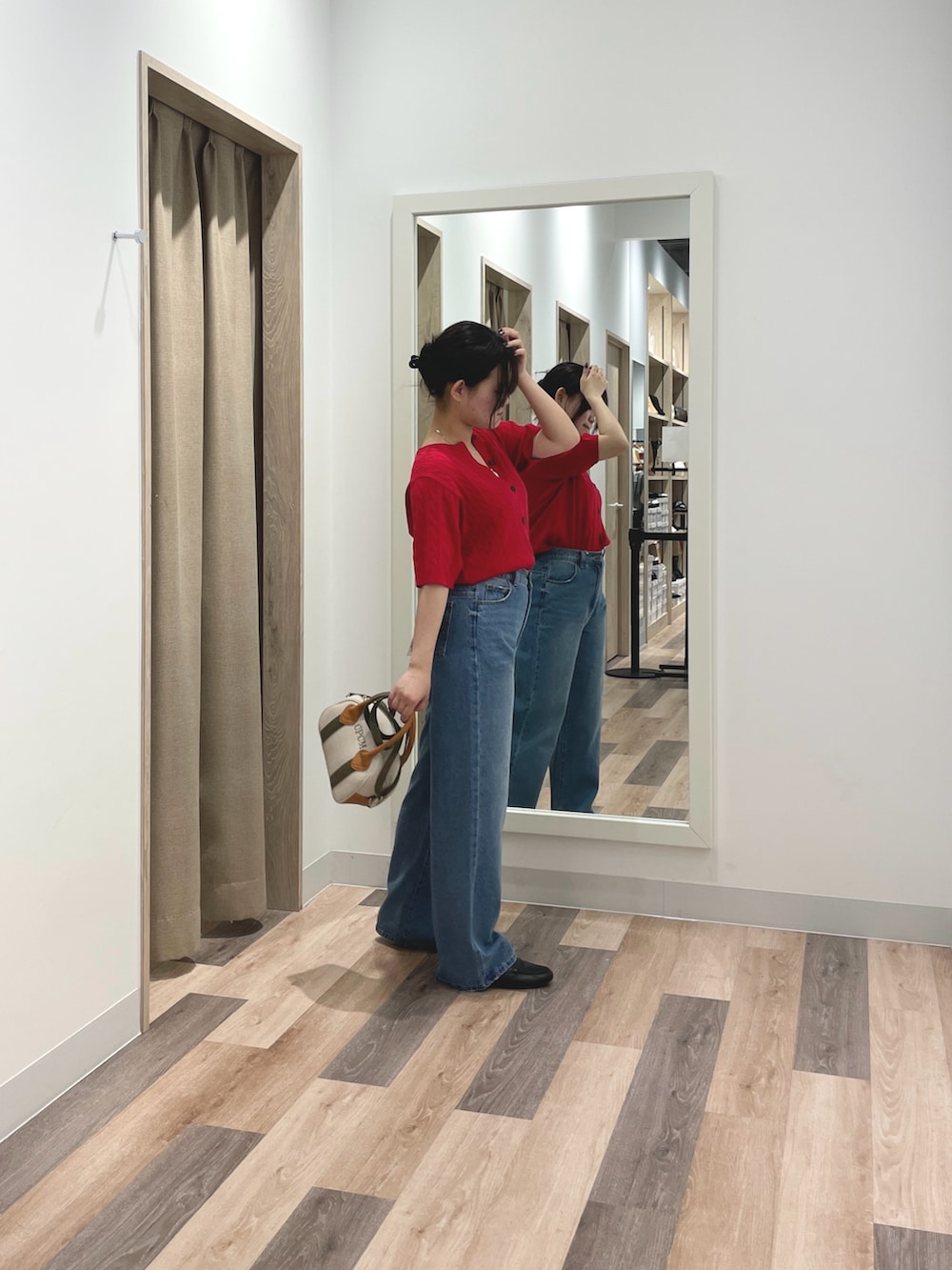 レッド系のニット/セーター、ブルー系のデニムパンツ、ホワイト系のトートバッグを着用したレディースの春コーディネートの3枚目の写真