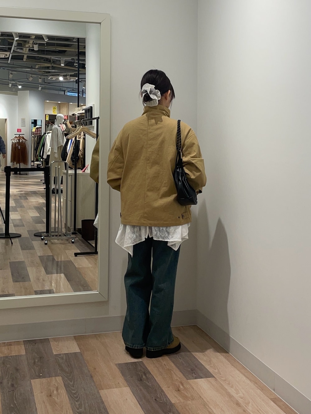 イエロー系のブルゾン、ホワイト系のシャツ/ブラウス、ブルー系のデニムパンツを着用したレディースの冬コーディネートの3枚目の写真