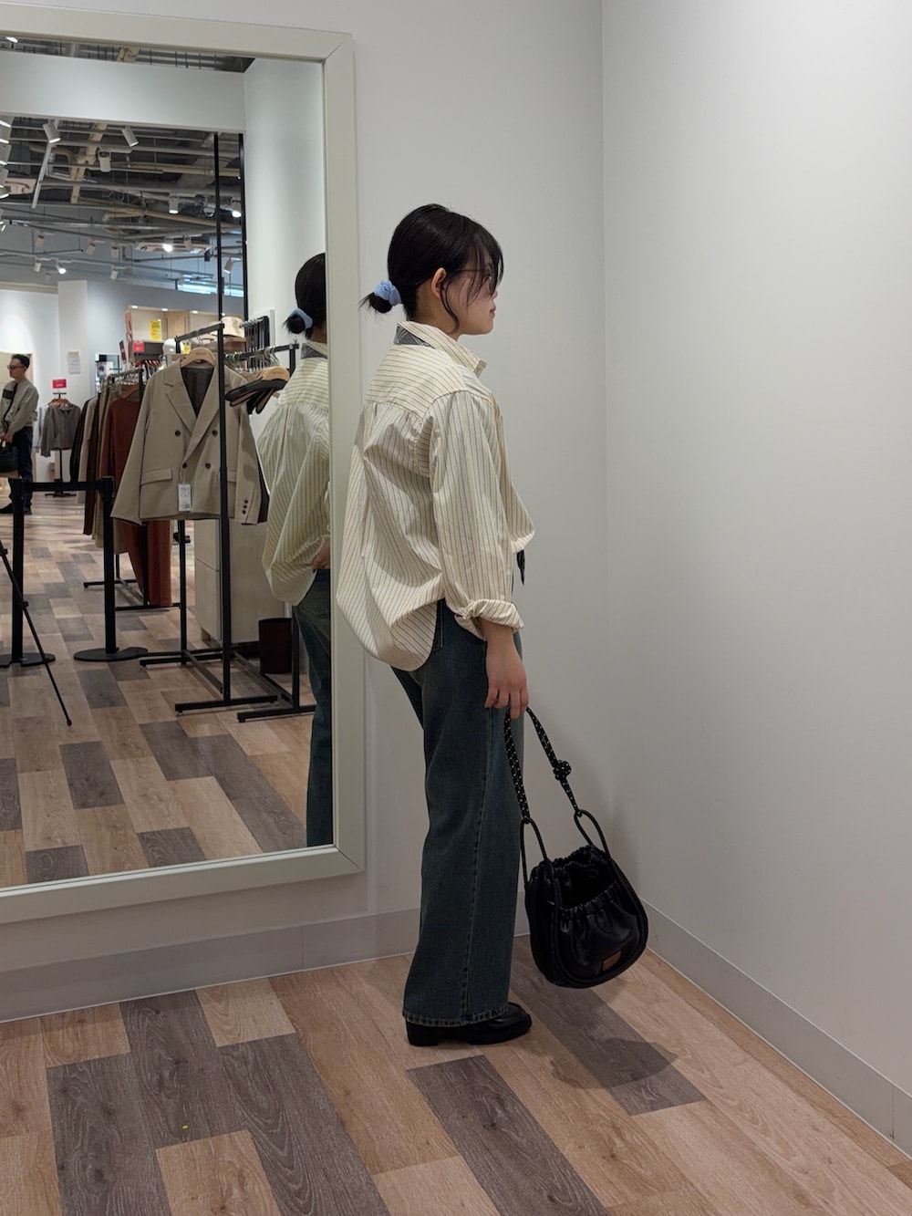 イエロー系のシャツ/ブラウス、ブルー系のデニムパンツ、ブラック系のショルダーバッグを着用したレディースの春コーディネートの2枚目の写真