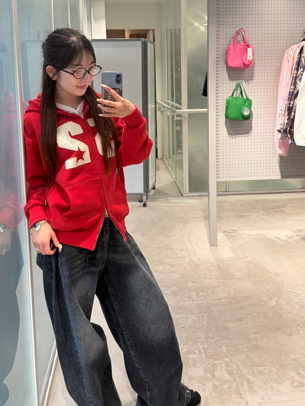 ブルー系のデニムパンツ、レッド系のパーカーを着用したレディースの春コーディネートの2枚目の写真