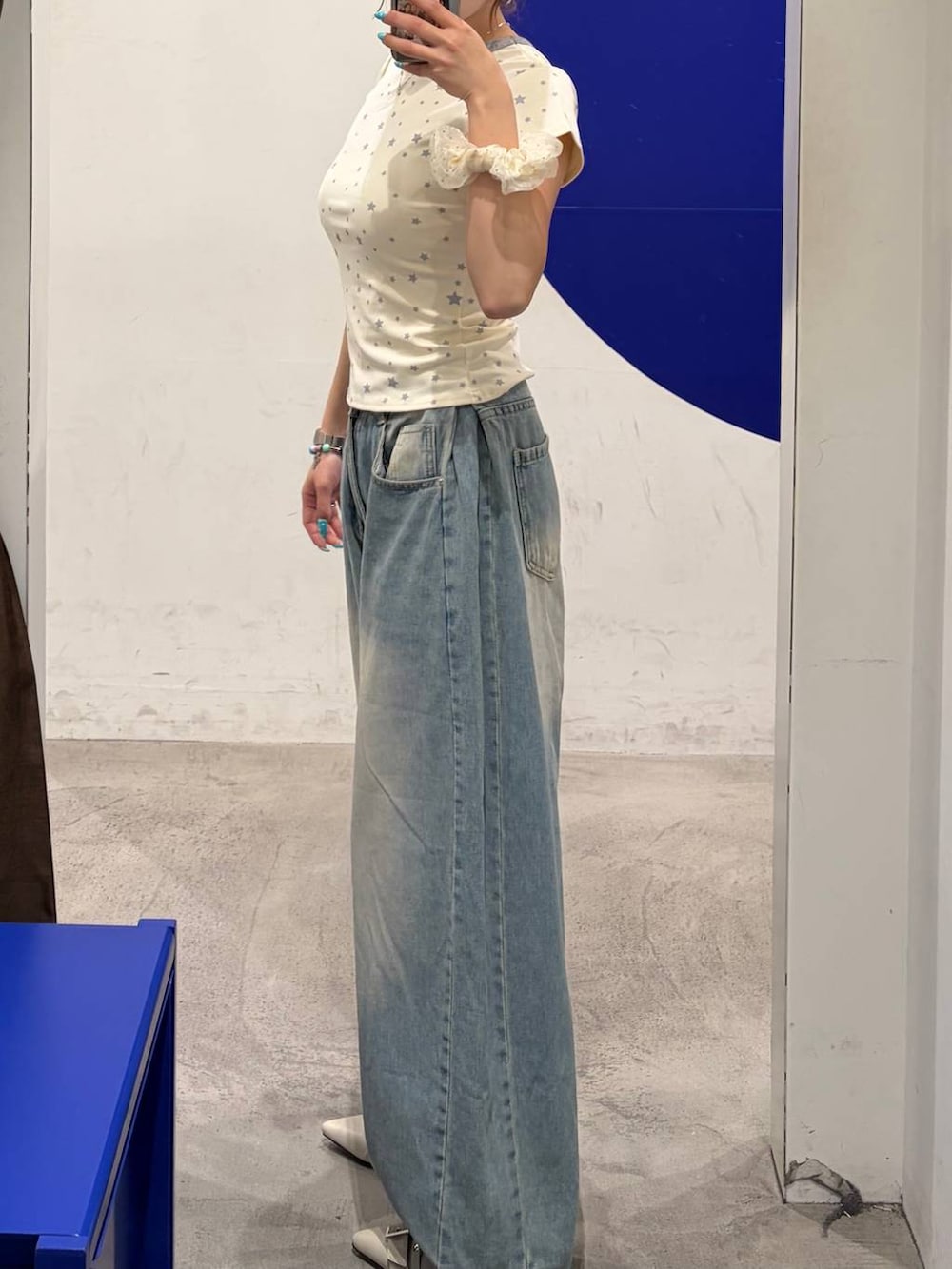ブルー系のデニムパンツ、ホワイト系のパンプス、ホワイト系のTシャツ/カットソーを着用したレディースの夏コーディネートの3枚目の写真