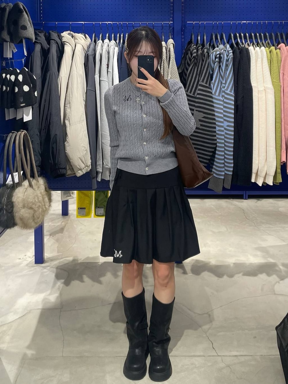 ブラック系のブーツ、ブラウン系のショルダーバッグ、ブラック系のスカートを着用したレディースの冬コーディネートの2枚目の写真