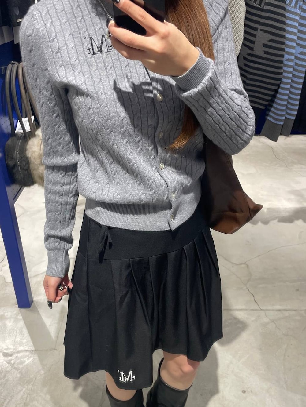 ブラック系のブーツ、ブラウン系のショルダーバッグ、ブラック系のスカートを着用したレディースの冬コーディネートの3枚目の写真