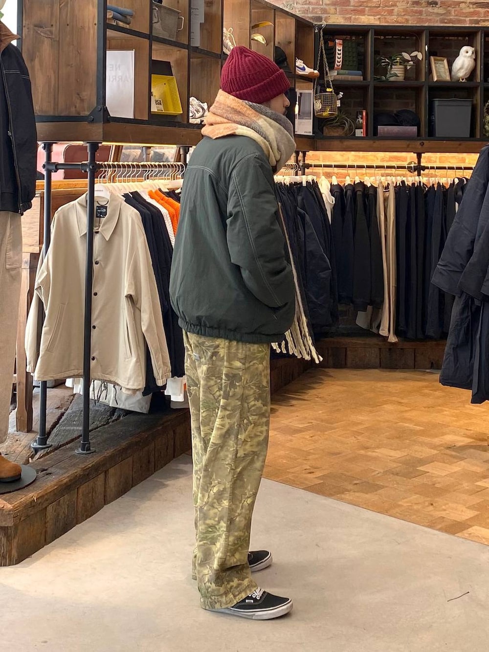 グリーン系のブルゾン、ベージュ系のその他パンツ、イエロー系のマフラーを着用したメンズの秋コーディネートの4枚目の写真