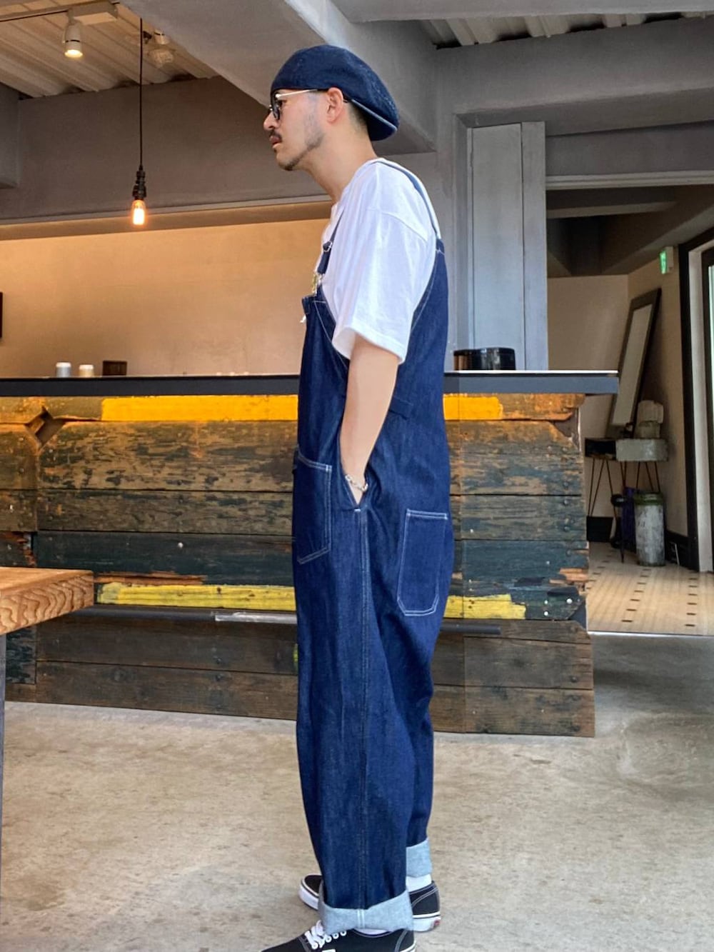 ブルー系のサロペット/オーバーオール、ホワイト系のTシャツ/カットソー、ブラック系のサングラスを着用したメンズの夏コーディネートの2枚目の写真