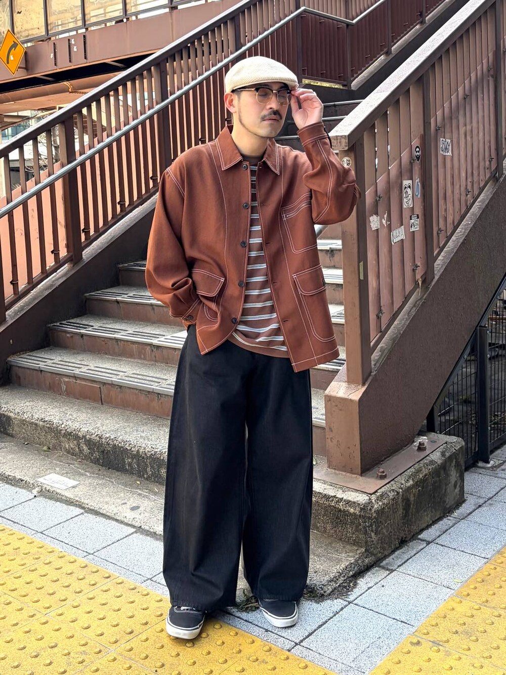 ブラウン系のカバーオール、ブラウン系のTシャツ/カットソー、ブラック系のデニムパンツを着用したメンズの春コーディネートの5枚目の写真