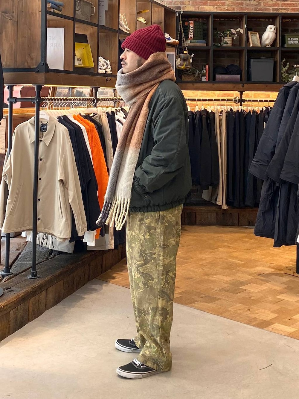 グリーン系のブルゾン、ベージュ系のその他パンツ、イエロー系のマフラーを着用したメンズの秋コーディネートの2枚目の写真