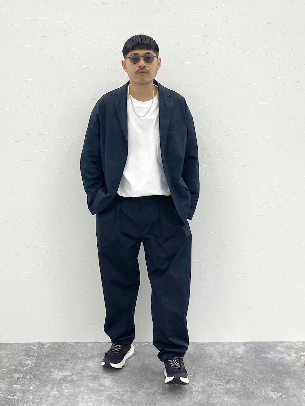 ブラック系のテーラードジャケット、ホワイト系のTシャツ/カットソー、ブラック系のスラックスを着用したメンズの夏コーディネートの2枚目の写真
