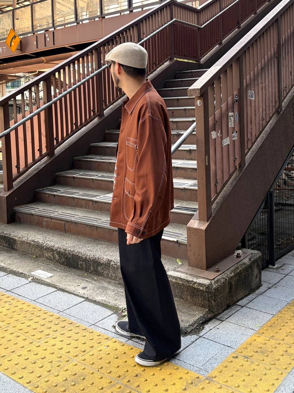 ブラウン系のカバーオール、ブラウン系のTシャツ/カットソー、ブラック系のデニムパンツを着用したメンズの春コーディネートの2枚目の写真