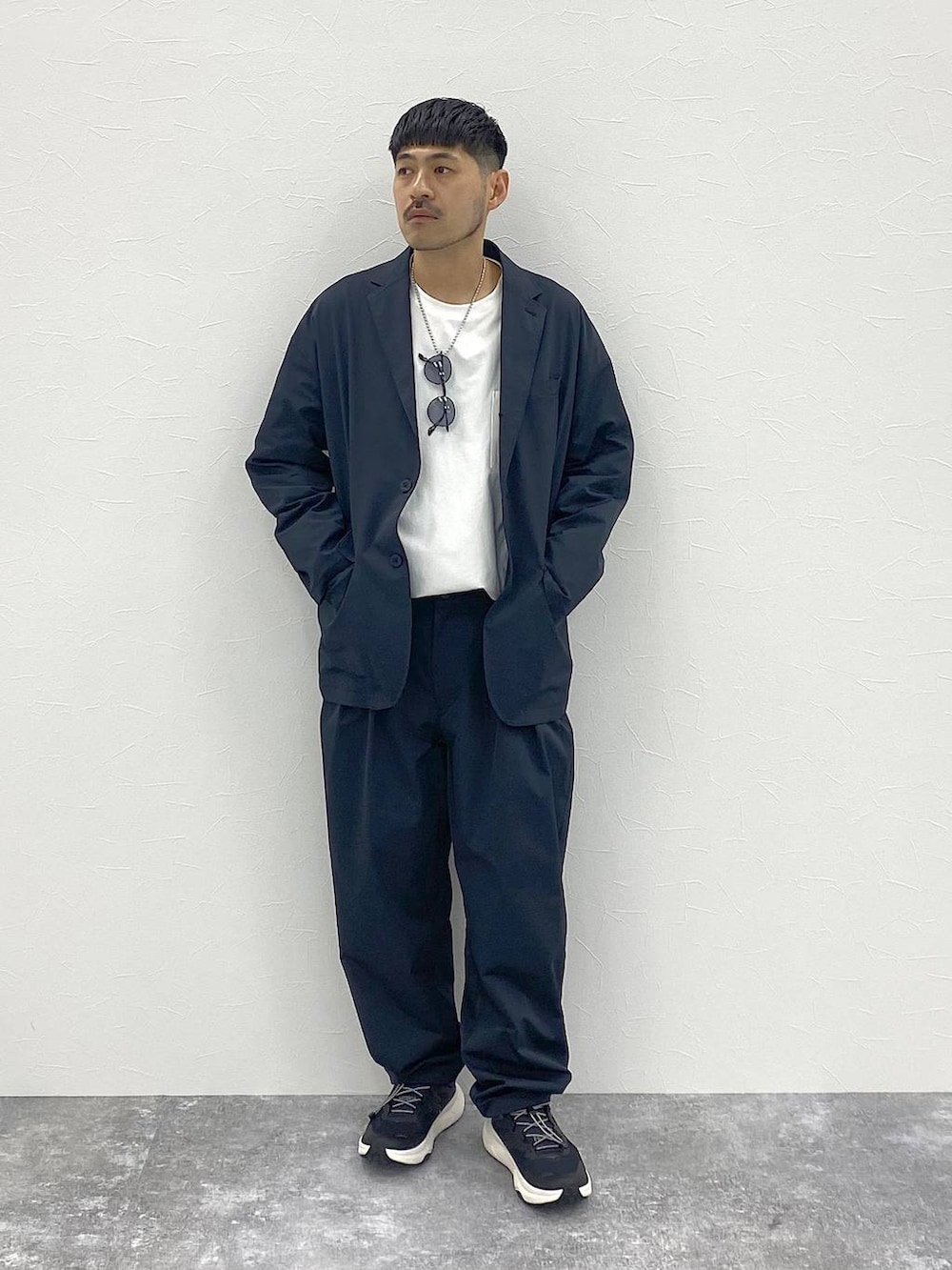 ブラック系のテーラードジャケット、ホワイト系のTシャツ/カットソー、ブラック系のスラックスを着用したメンズの夏コーディネートの7枚目の写真