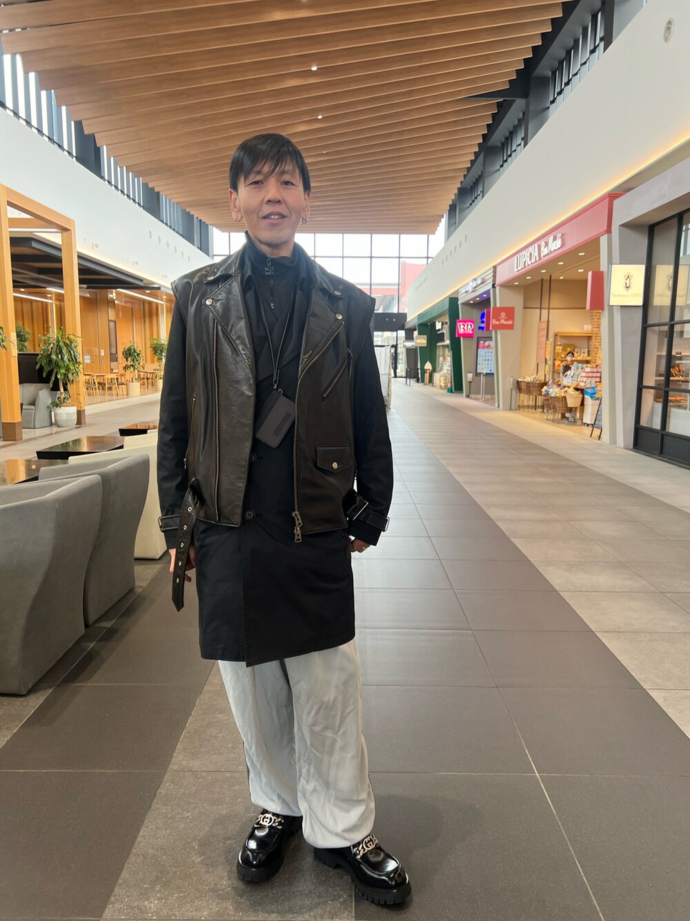 ブラック系のローファー、グレー系のその他パンツ、ブラック系のトレンチコートを着用したメンズの冬コーディネートの2枚目の写真