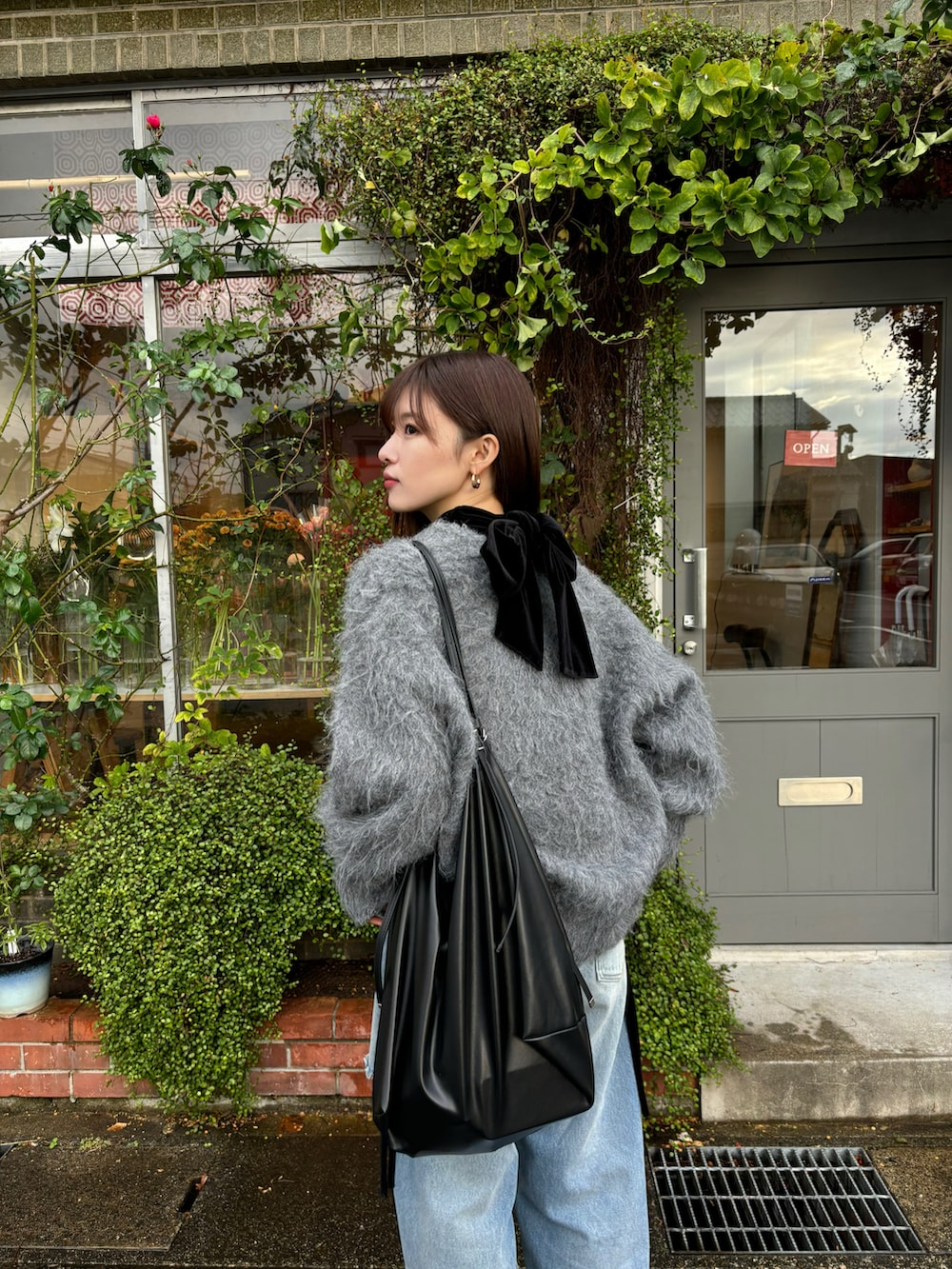 ブラック系のTシャツ/カットソー、グレー系のカーディガン/ボレロ、ブルー系のデニムパンツを着用したレディースの冬コーディネートの4枚目の写真