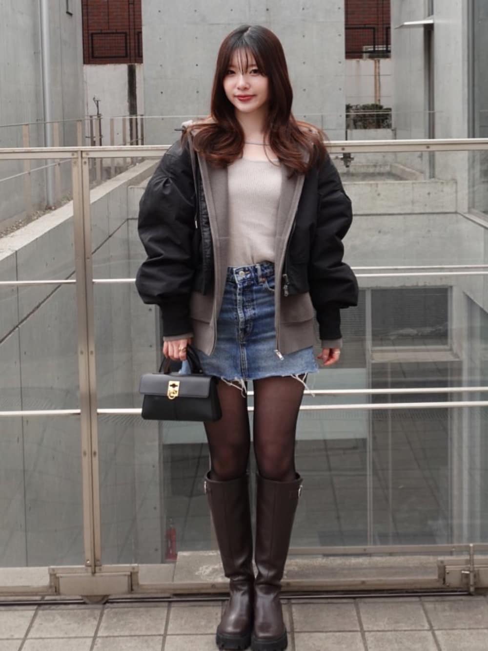 ブラック系のブルゾン、ブラウン系のブーツを着用したレディースの春コーディネートの2枚目の写真