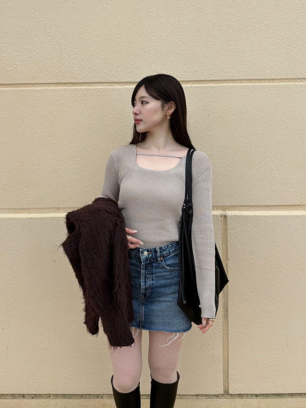 ブルー系のデニムスカート、ブラック系のブーツ、ベージュ系のTシャツ/カットソーを着用したレディースの冬コーディネートの3枚目の写真