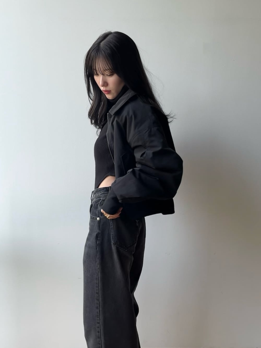 ブラック系のニット/セーター、ブラック系のブルゾン、ブラック系のデニムパンツを着用したレディースの冬コーディネートの2枚目の写真