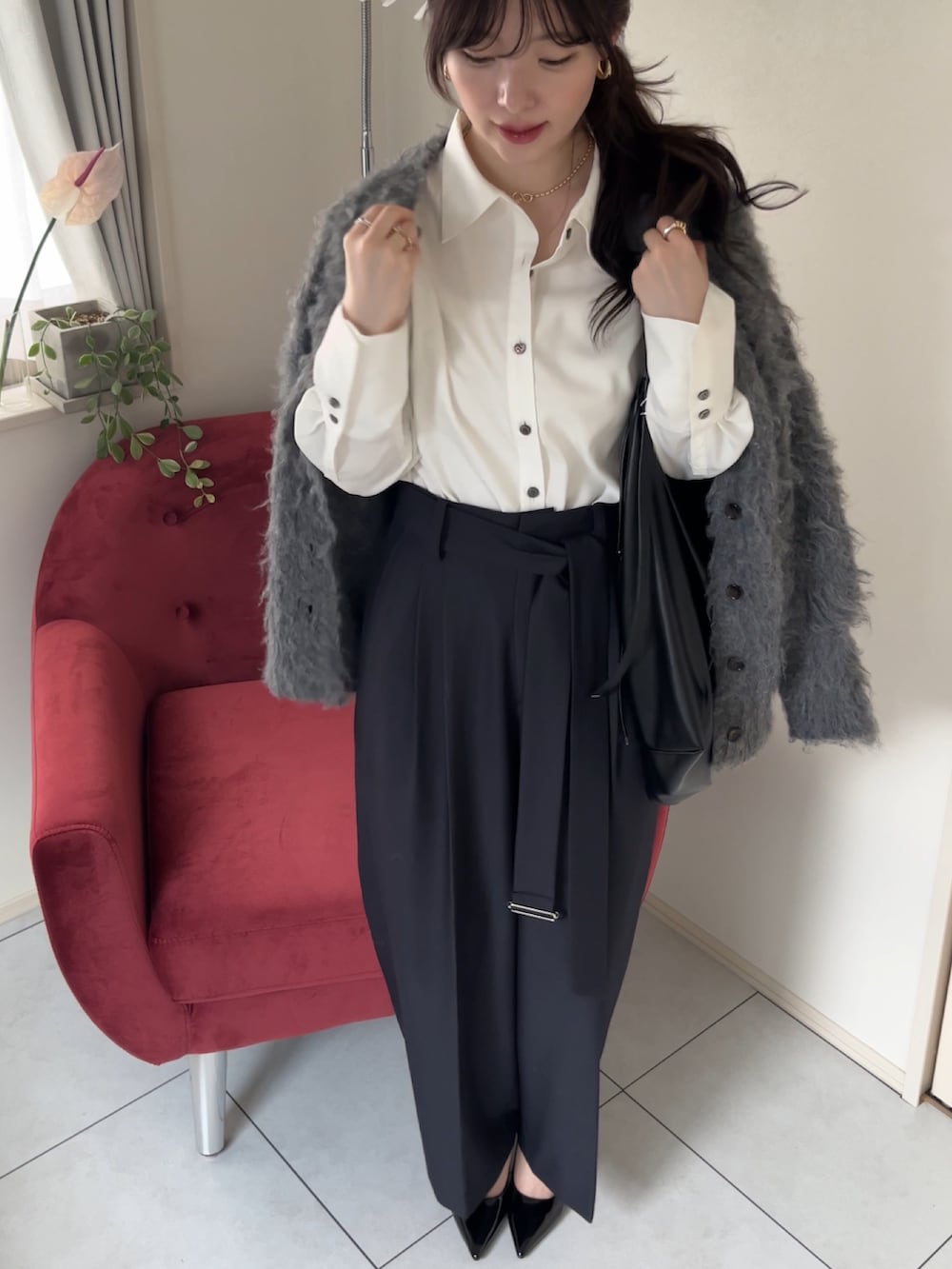 グレー系のスラックス、ブラック系のショルダーバッグ、ホワイト系のシャツ/ブラウスを着用したレディースの冬コーディネートの2枚目の写真