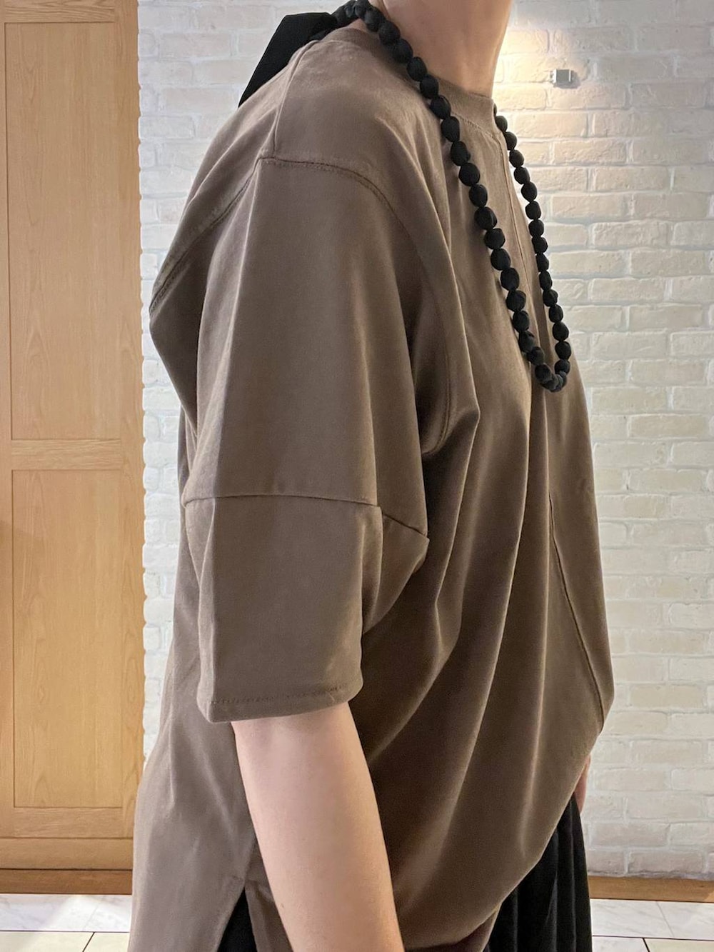 ブラック系のその他パンツ、ブラウン系のTシャツ/カットソー、ブラック系のネックレスを着用したレディースの夏コーディネートの6枚目の写真