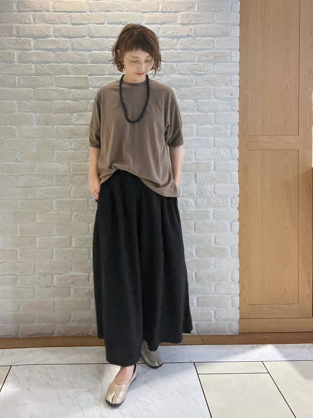 ブラック系のその他パンツ、ブラウン系のTシャツ/カットソー、ブラック系のネックレスを着用したレディースの夏コーディネートの2枚目の写真
