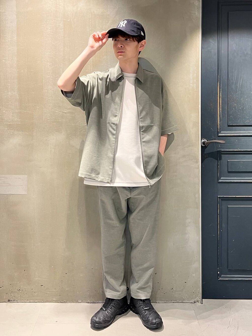 ブラック系のスニーカー、グレー系のスラックス、ホワイト系のTシャツ/カットソーを着用したメンズの春コーディネートの2枚目の写真