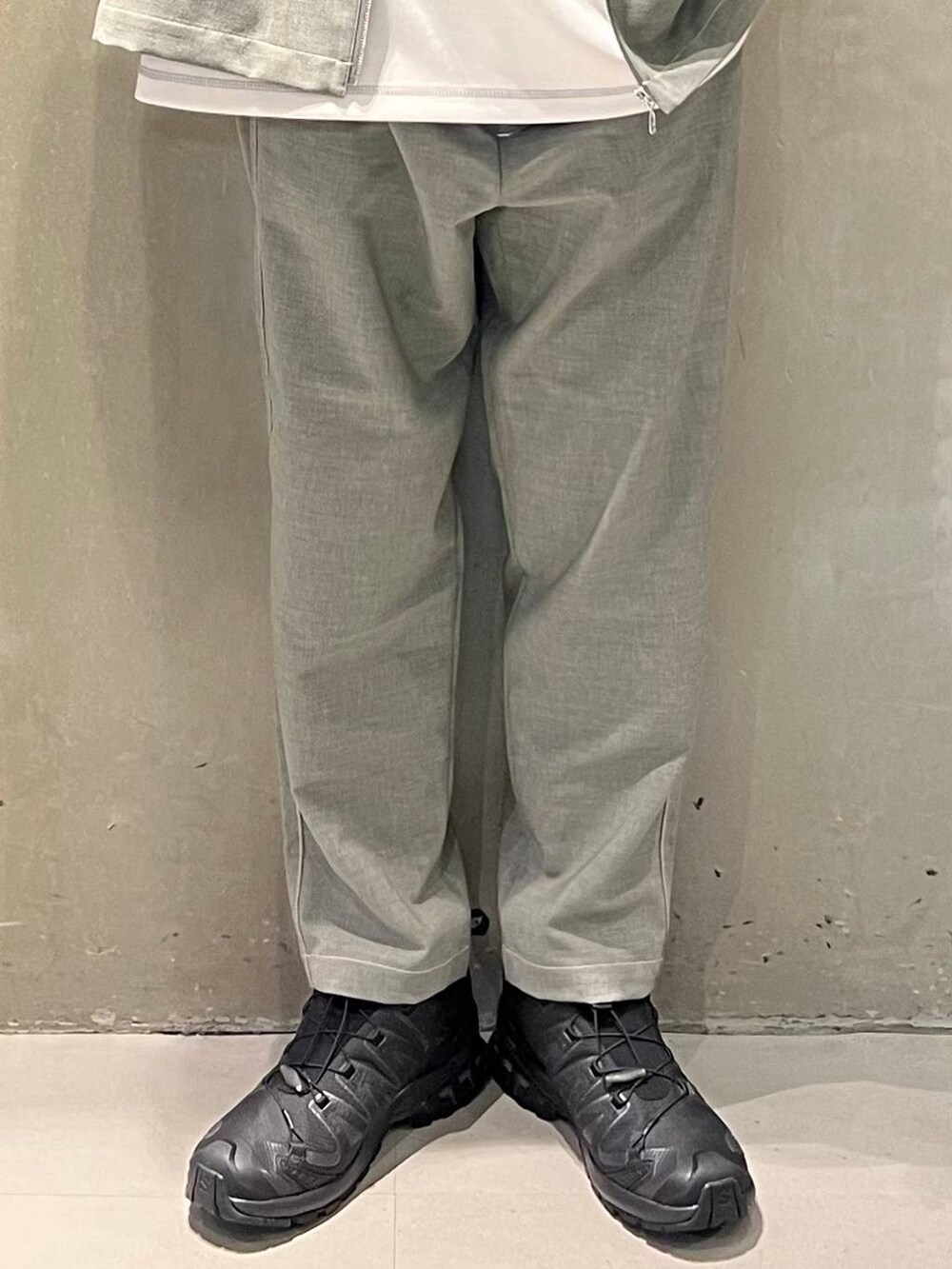 ブラック系のスニーカー、グレー系のスラックス、ホワイト系のTシャツ/カットソーを着用したメンズの春コーディネートの3枚目の写真