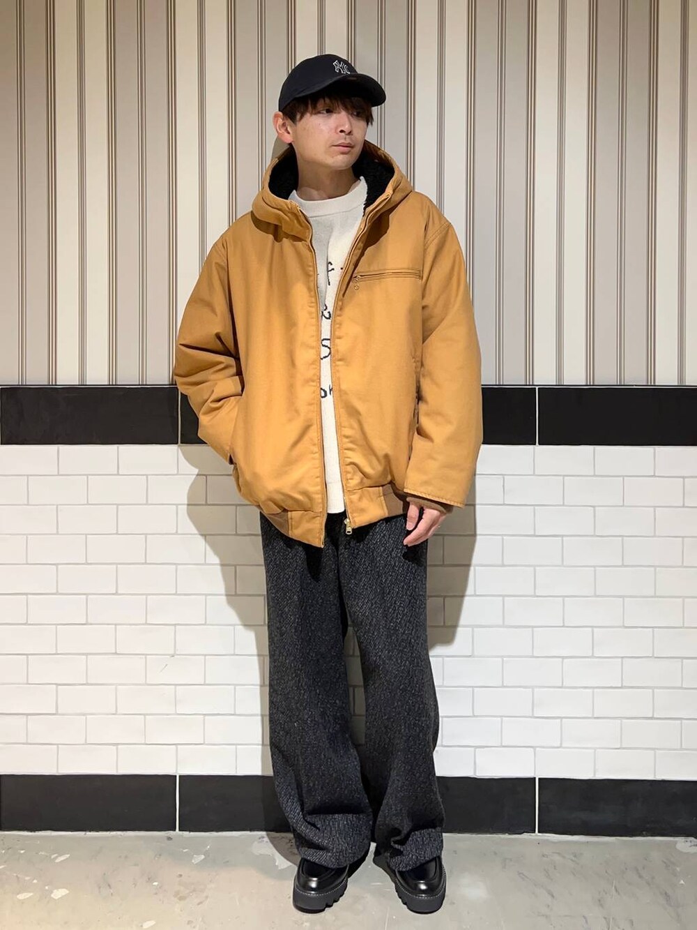 ブラウン系のブルゾン、ブラック系のドレスシューズ、グレー系のスラックスを着用したメンズの秋コーディネートの2枚目の写真