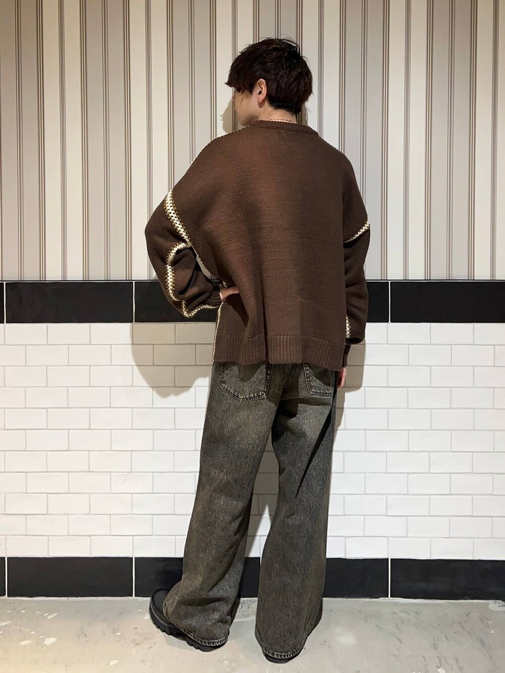 ブラック系のドレスシューズ、ブラウン系のニット/セーター、グレー系のデニムパンツを着用したメンズの冬コーディネートの6枚目の写真