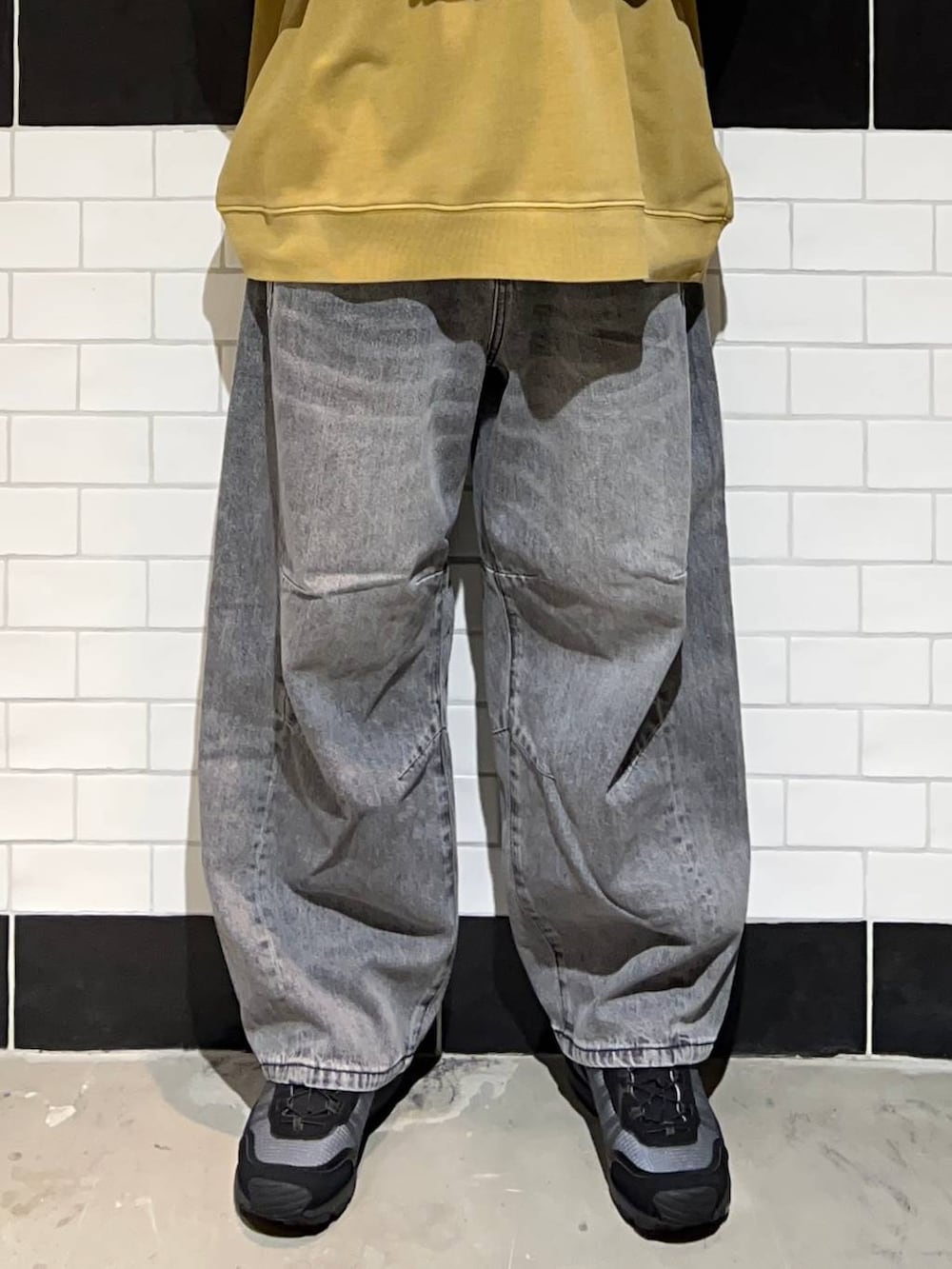 ブラック系のブルゾン、グレー系のデニムパンツ、ブラック系のスニーカーを着用したメンズの秋コーディネートの3枚目の写真