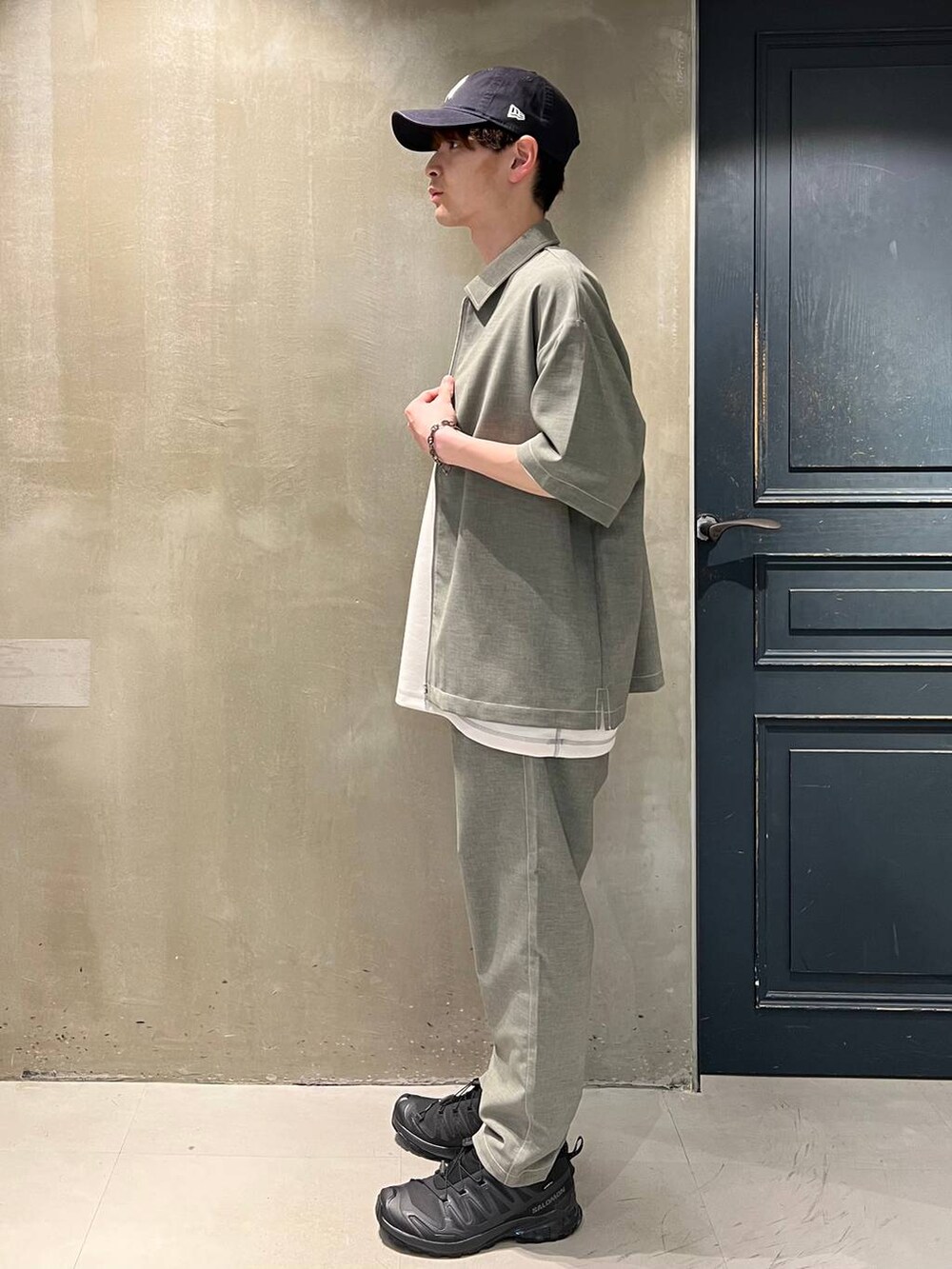 ブラック系のスニーカー、グレー系のスラックス、ホワイト系のTシャツ/カットソーを着用したメンズの春コーディネートの5枚目の写真