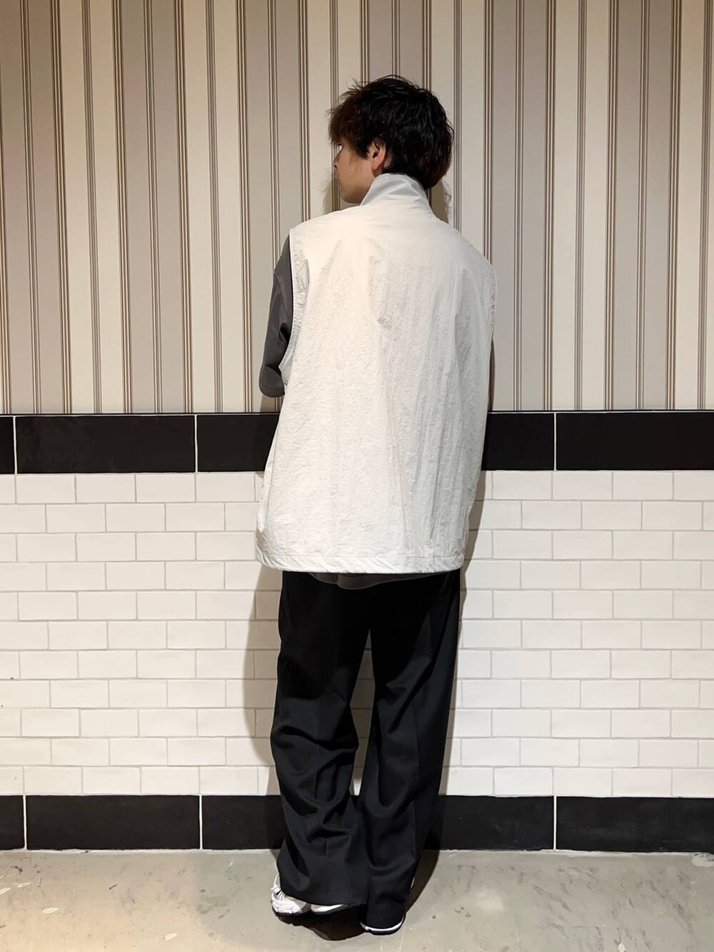 ホワイト系のスニーカー、グレー系のTシャツ/カットソー、ブラック系のスラックスを着用したメンズの夏コーディネートの5枚目の写真