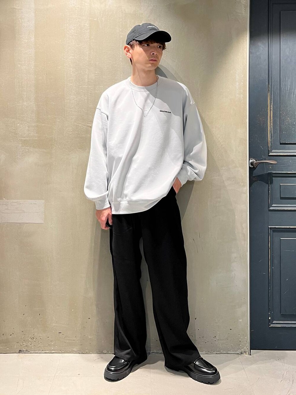 ブラック系のスラックス、グレー系のスウェット、ブラック系のキャップを着用したメンズの秋コーディネートの2枚目の写真