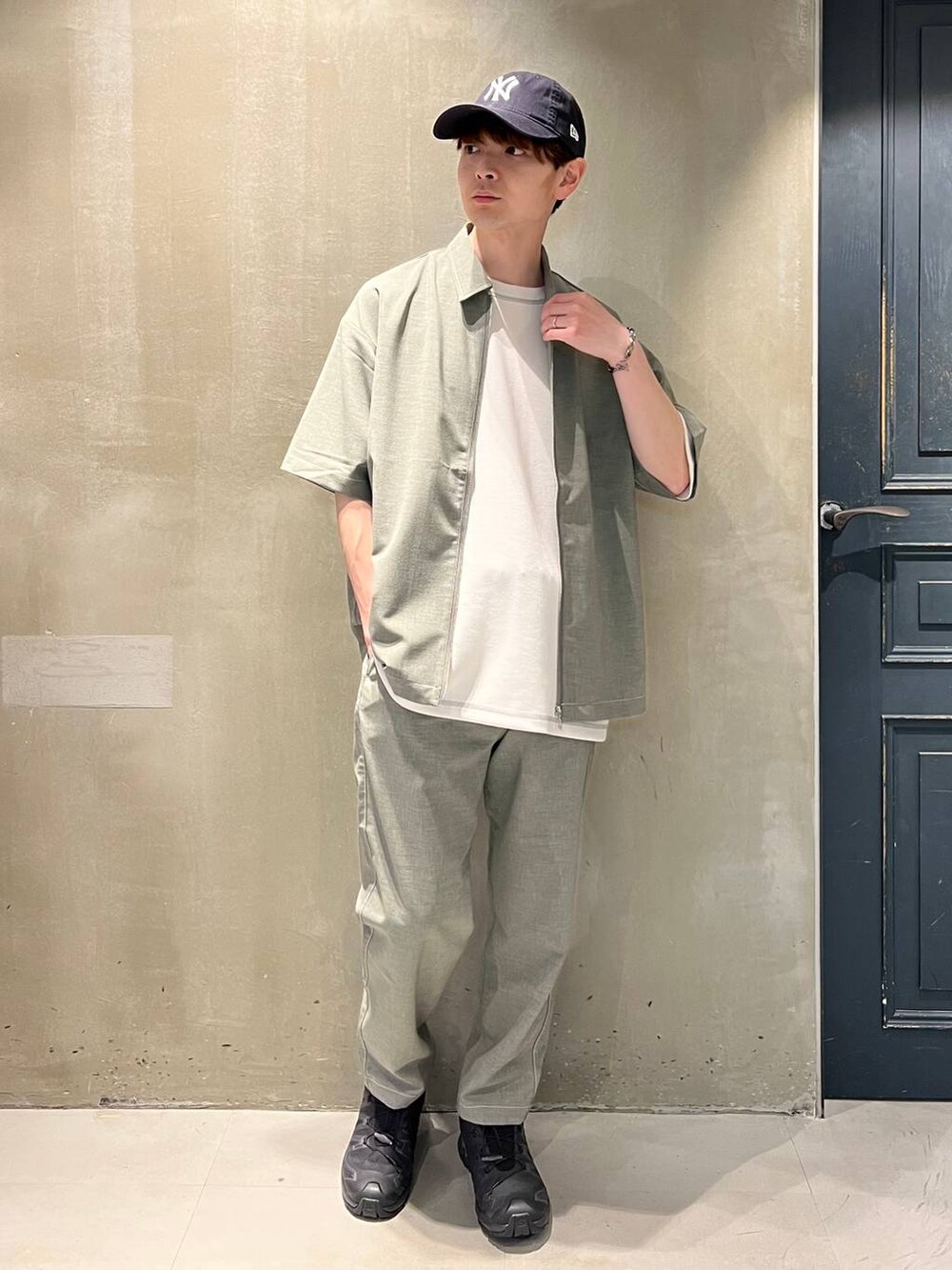 ブラック系のスニーカー、グレー系のスラックス、ホワイト系のTシャツ/カットソーを着用したメンズの春コーディネートの4枚目の写真