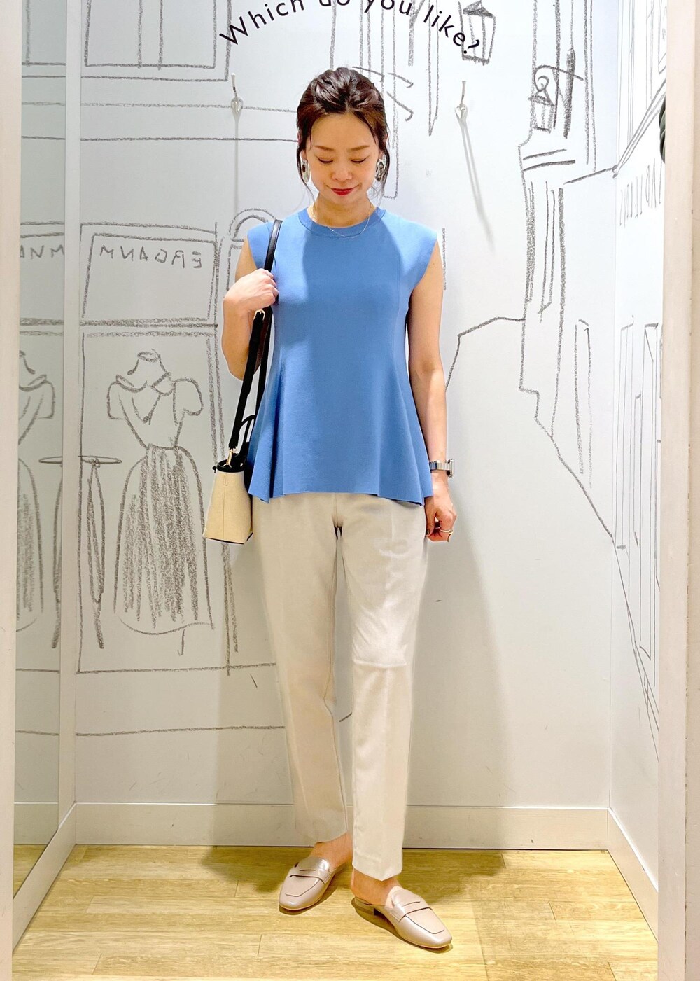 ブルー系のニット/セーター、ブラック系のトートバッグ、グレー系のスラックスを着用したレディースの夏コーディネートの2枚目の写真