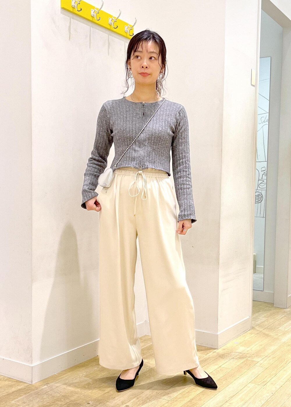 ブラック系のパンプス、シルバー系のショルダーバッグ、ブラック系のニット/セーターを着用したレディースの春コーディネートの3枚目の写真