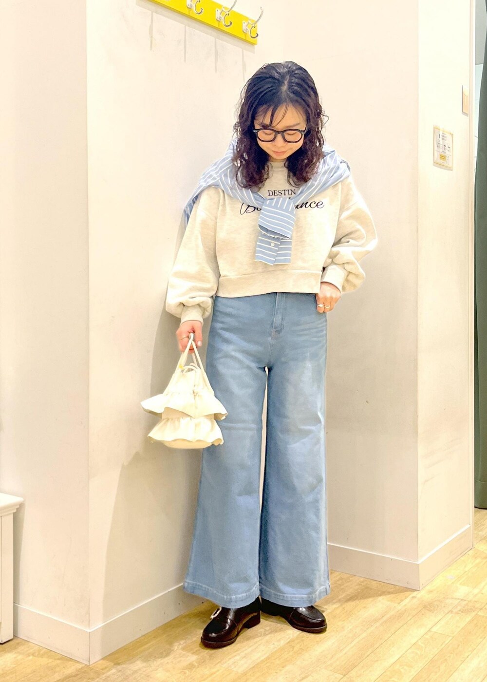 ホワイト系のショルダーバッグ、ブラック系のローファー、グレー系のスウェットを着用したレディースの冬コーディネートの2枚目の写真