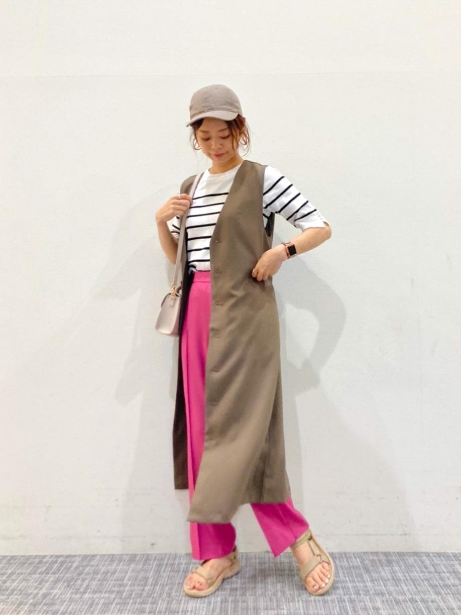 ピンク系のスラックス、ベージュ系のショルダーバッグ、ホワイト系のニット/セーターを着用したレディースの夏コーディネートの2枚目の写真