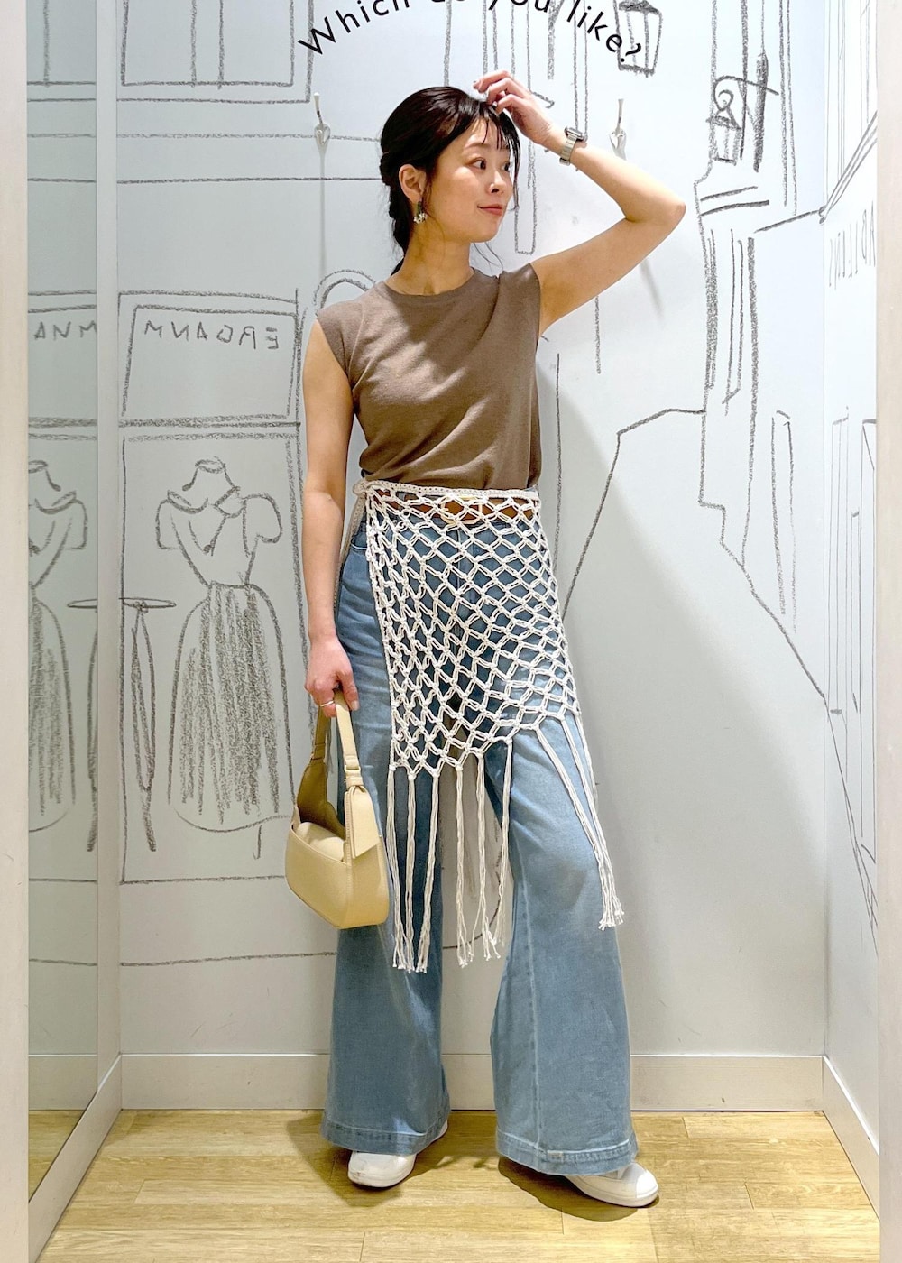 ベージュ系のハンドバッグ、ブルー系のデニムパンツ、ホワイト系のスカートを着用したレディースの春コーディネートの3枚目の写真