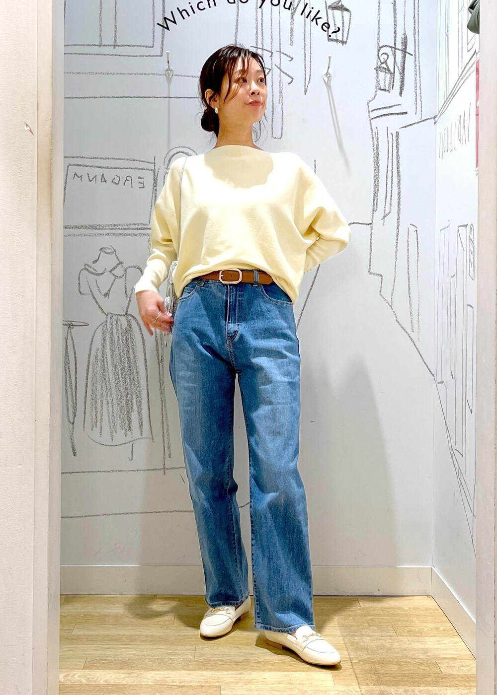 ホワイト系のマウンテンパーカー、シルバー系のショルダーバッグ、ブルー系のデニムパンツを着用したレディースの冬コーディネートの3枚目の写真