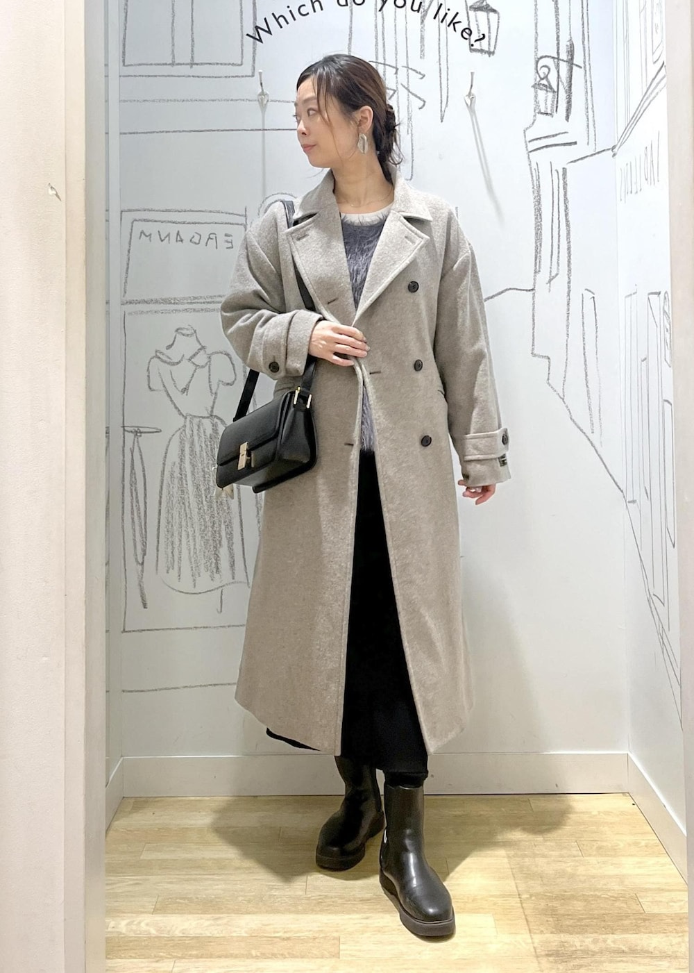ブラック系のショルダーバッグ、ブラック系のスカート、ベージュ系のチェスターコートを着用したレディースの冬コーディネートの2枚目の写真