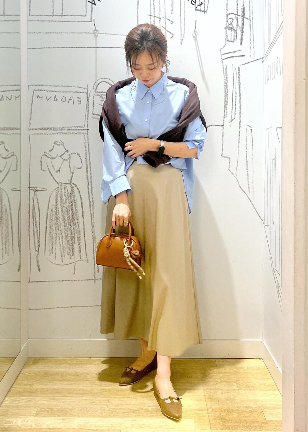 ベージュ系のスカート、ブラウン系のパンプス、ブルー系のシャツ/ブラウスを着用したレディースの秋コーディネートの2枚目の写真