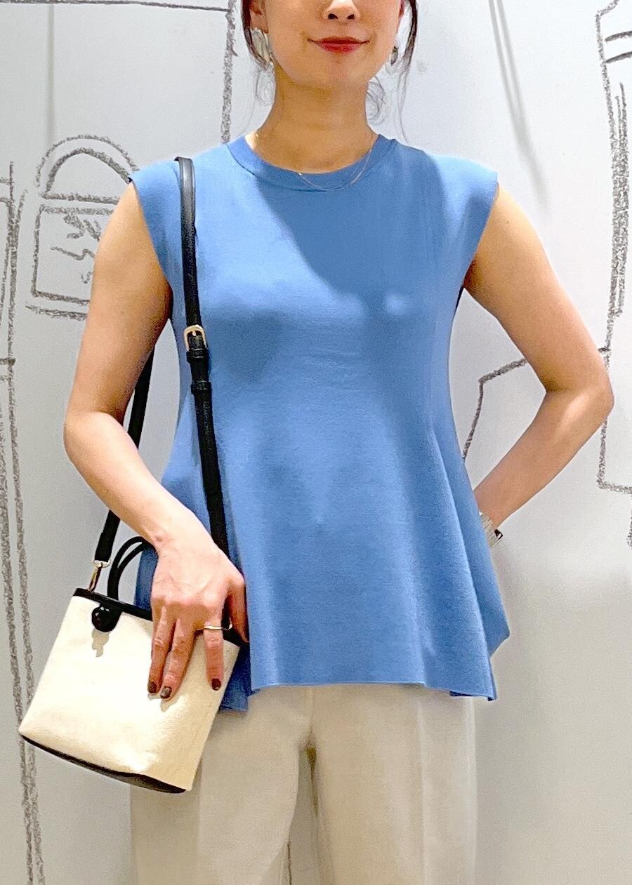 ブルー系のニット/セーター、ブラック系のトートバッグ、グレー系のスラックスを着用したレディースの夏コーディネートの7枚目の写真