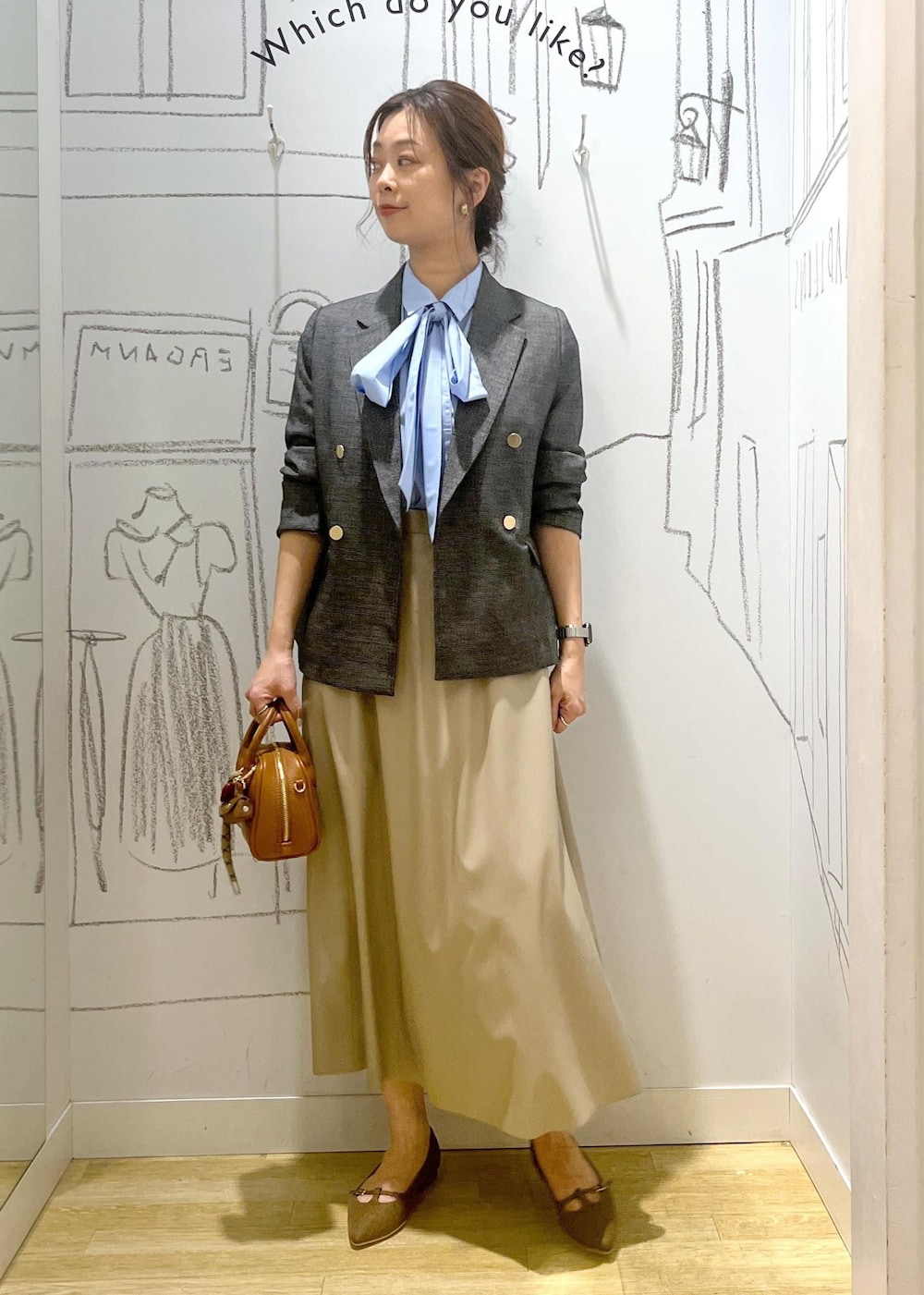 グレー系のテーラードジャケット、ベージュ系のスカート、ブラウン系のパンプスを着用したレディースの秋コーディネートの3枚目の写真