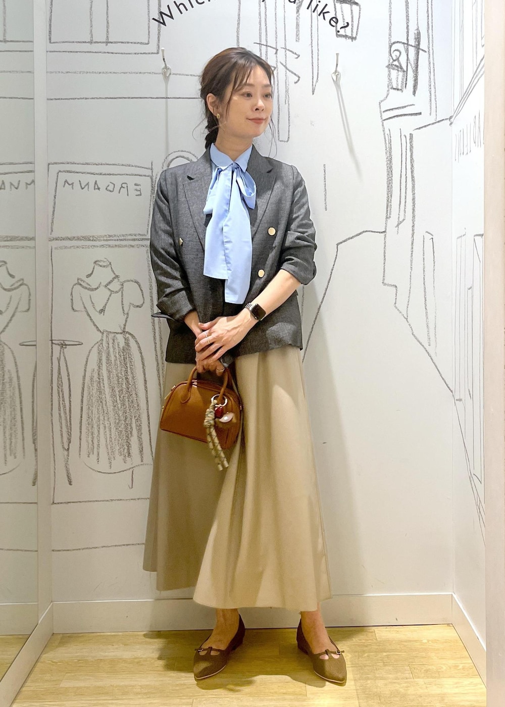グレー系のテーラードジャケット、ベージュ系のスカート、ブラウン系のパンプスを着用したレディースの秋コーディネートの2枚目の写真
